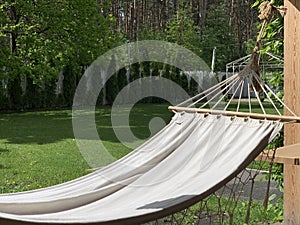 Empty hammock to relax on the terrace of the house. A hammock hangs in the yard in a green garden. Concept: camping, weekend