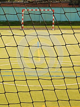 Empty handball gate. Outdoor football or handball playground, plastic light green surface on ground