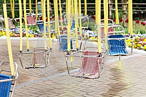 Empty hanging seats of a children's carousel in an amusement park. Selective focus.