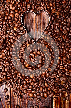 Empty Heart shape made inside of coffee beans background. Flat lay. Symbol of Love to coffee. Vertical wooden wallpaper