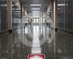 Empty high school hallway with one way sign on floor