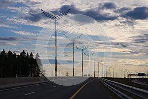 Empty highway against evening sky, row of light pillars,