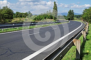 Empty highway passing landscape trees