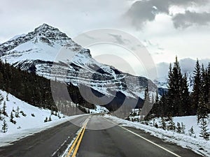 An empty highway on a snowy winter landscape going through the rocky mountains on a nice winter day in jasper national park photo