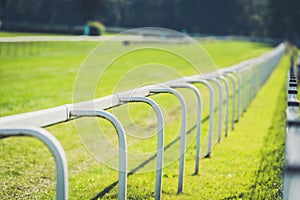 Empty horse race track with green grass and white fence
