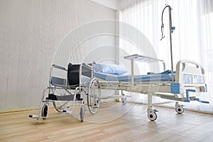 Empty hospital ward room with bed and wheelchair