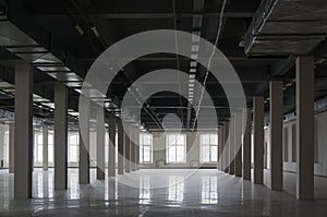 Empty huge open space in old factory building with rows of columns, big windows and pipes on the ceiling