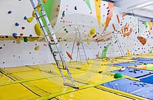 Empty indoor bouldering gym with ladders next to climbing walls