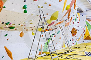Empty indoor bouldering gym with ladders next to climbing walls