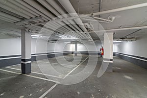 Empty industrial parking garage with concrete floors and ceilings, illuminated by bright lights