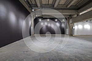 Empty interior of large concrete room as warehouse or hangar with spotlights