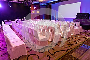 Empty interior of luxury conference hall or seminar room with projector screen, white chairs