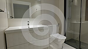 Empty Interior of modern gray bathroom with mirror, sink, toilet and shower with glass partition