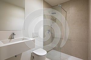 Empty Interior of modern white bathroom with mirror, sink, toilet and shower with glass partition