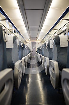 Empty interior of a passenger train car aka coach or carriage . Rows of unoccupied seats and folding tables in economy