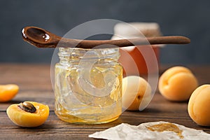 Empty jar of eaten apricot jam. Empty glass jar of homemade apricot jam, spoon and ripe apricot fruits on table