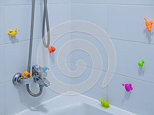 Empty kid`s bathroom with white tiles and lot of sticky colorful toys on walls