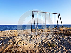 Empty kids swing on a deserted beach