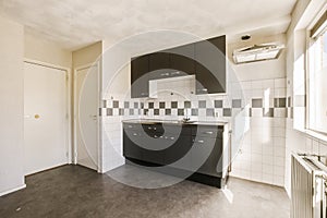 an empty kitchen with black cabinets and white tiled