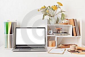 Empty laptop screen, desktop organizer with desk shelves and office supplies