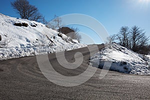 Empty, large mountain road with snow on sides, clear blue sky