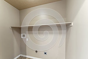 Empty laundry room interior with wall mounted shelf