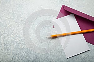 Empty letter, purple envelope and pencil on a vintage white background. Copy space