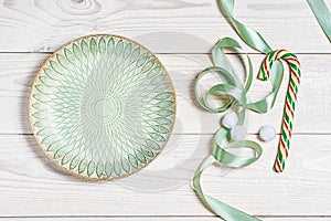 Empty light green plate, lollipop and decorations shot top view, flat lay