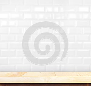 Empty light wood table and white ceramic tile brick wall in back