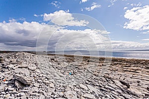 Empty limestone rocky beach of the island of Inis Oirr with the Atlantic Ocean and the Plassey shipwreck in the background