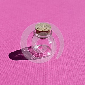 Empty little bottles with cork stopper on pink background