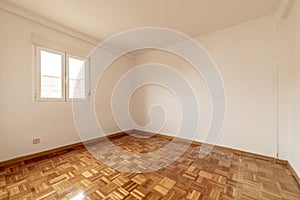 Empty living room with newly slashed and varnished oak lattice parquet floor, smooth white painted walls and white aluminum window