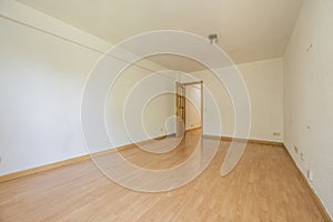 Empty living room with oak parquet flooring, plain white walls and oak woodwork