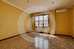 Empty living room with oak parquet, white aluminum radiators under a long