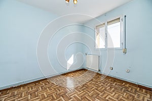 Empty living room with wooden parquet flooring, blue painted walls