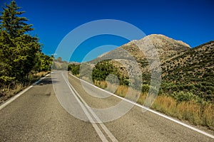 Empty lonely car road in south country side highland environment with mountain background landscape in clear weather time, driving