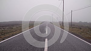 An empty lonely eerie road is covered with fog during the day