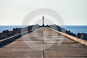 Empty long concrete pier with breakwaters and signal lighthouse in European port, copy space