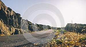 Empty long mountain road to the horizon on a sunny summer day at bright sunset