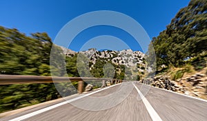 Empty long mountain road to the horizon on a sunny summer day at bright sunset