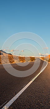 Empty long nevada mountain road to the horizon on a sunny summer day at bright sunset. vertical image for your reel and story