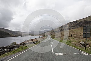 An empty long road surrounded by green hills