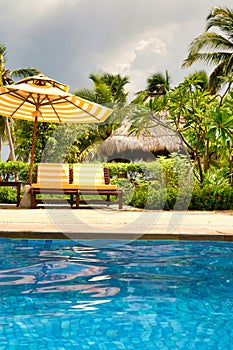 Empty lounge chairs by the crystal blue pool on Hainan Island.