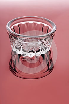 Empty low glass cup on a red background.