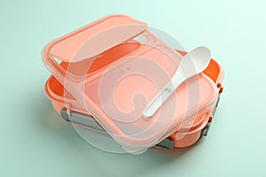 Empty lunch box with spoon on light blue background