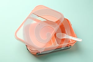 Empty lunch box with spoon on light blue background
