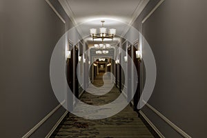 Empty luxurious hotel corridor lit by chandeliers