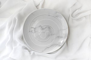 Empty marble plate on white silk background. Elegant minimalist wedding table setting
