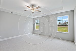 Empty master bedroom with gray walls, a ceiling fan, and windows