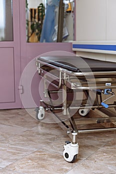 Empty mechanical trolley for patients in the hospital corridor. Ambulance trolley. Trolley for transporting patients. Medical